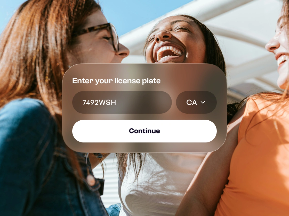 Amigas riendo detrás de una tarjeta para ingresar la placa